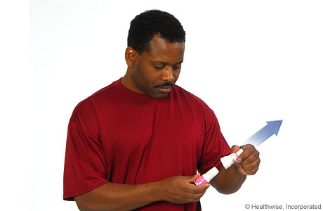 A man removing the cap from the inhaler