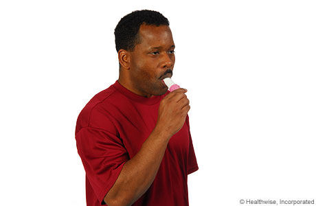 A man placing the inhaler in his mouth